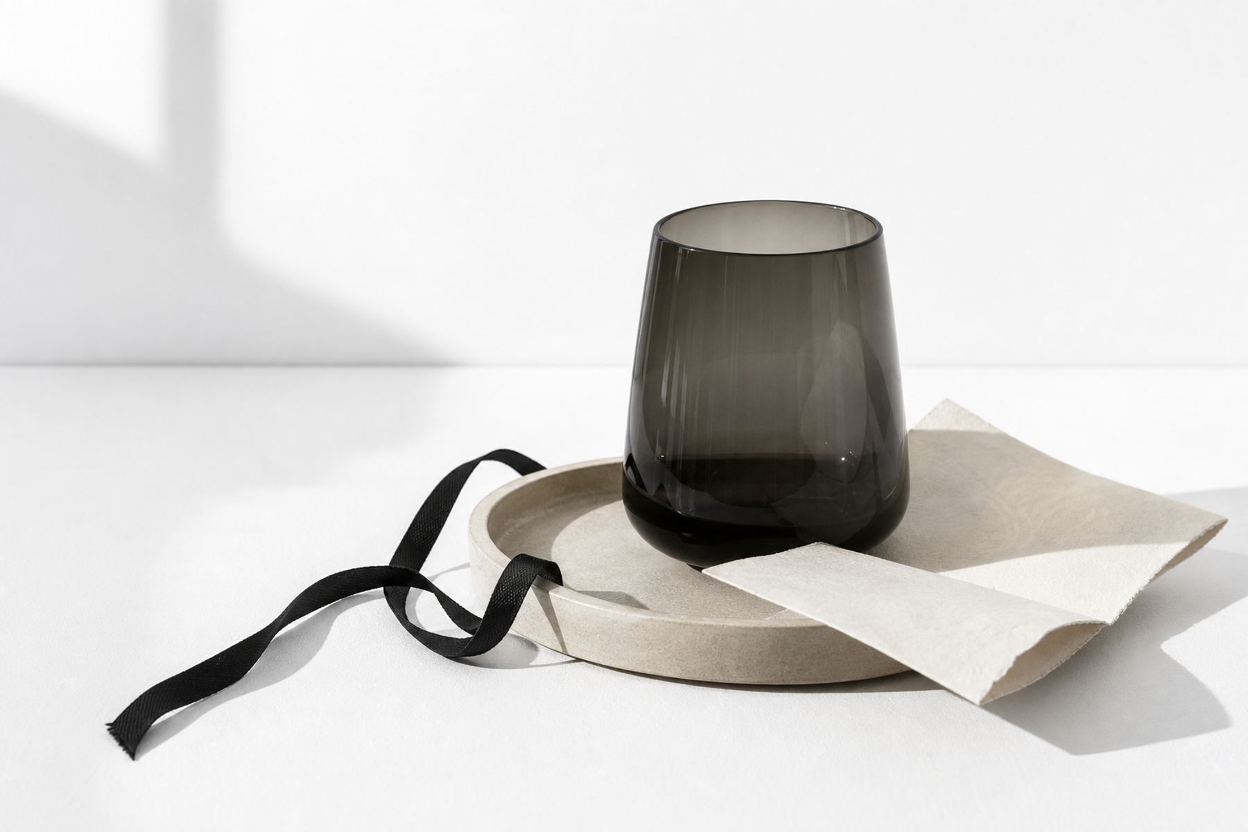 Dark glass vessel and linen on a sunlit surface.